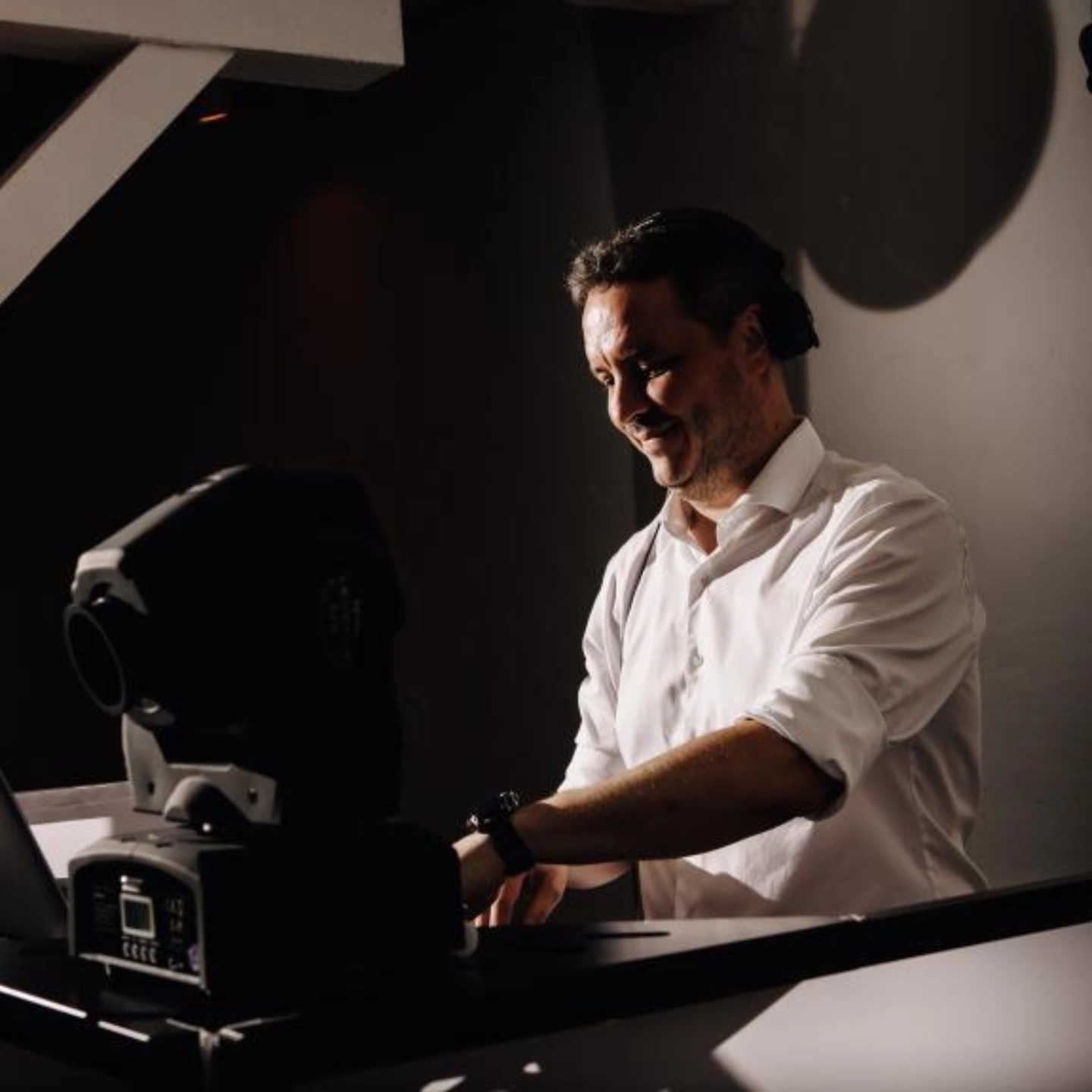 DJ Sven Pfaffmann-Jaekel an den Decks, weißes Hemd, warmes Licht im dunklen Raum