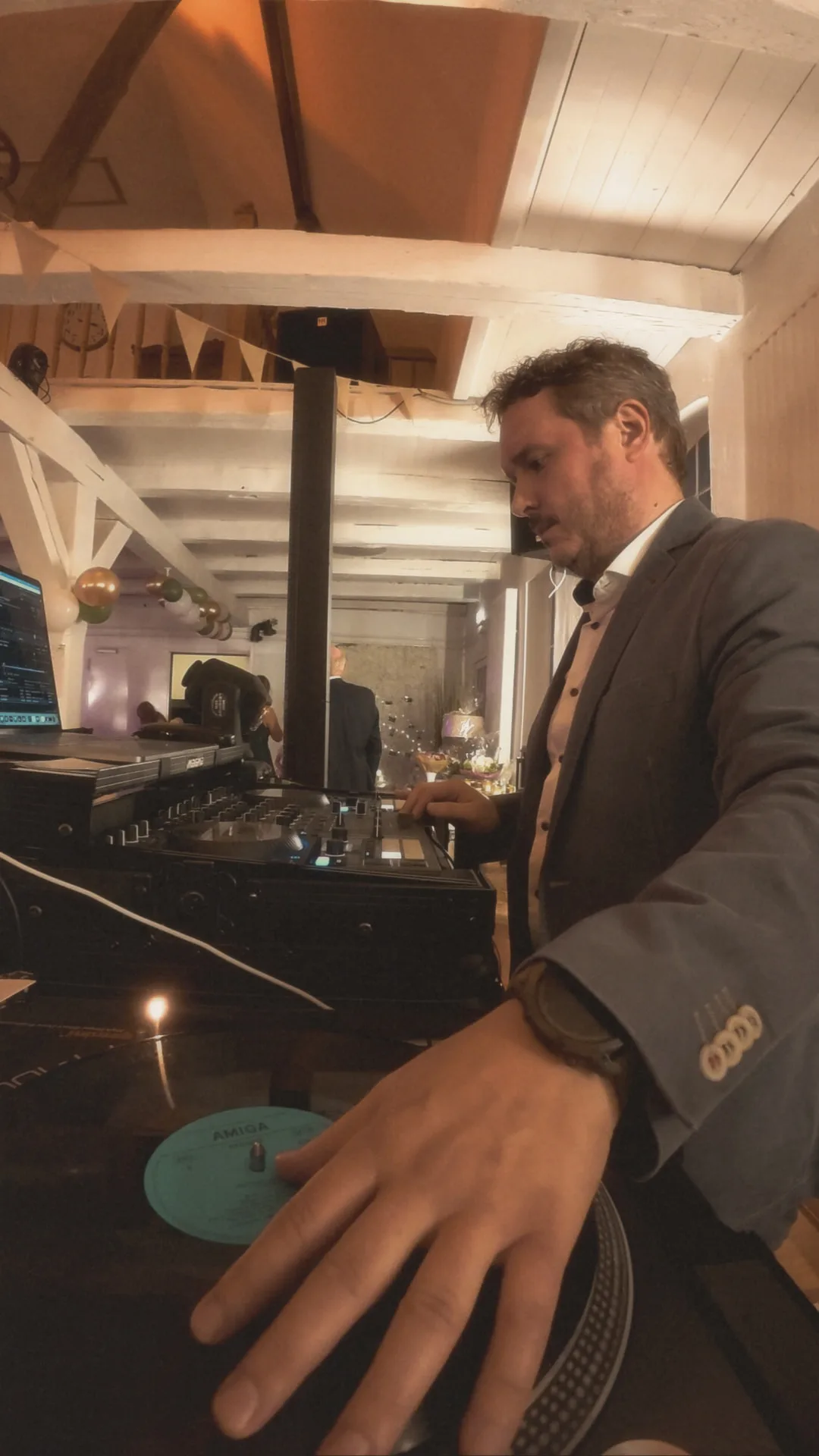 DJ Sven legt beim Sektempfang Vinyl auf – Hand am Plattenteller, warmes Licht in der Scheune